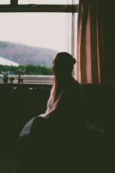 白天，窗边坐着一位凝视窗外的女人剪影