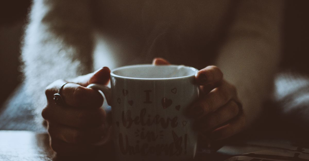 close-up of hands holding a warm mug, steam rising, with a calm, focused expression
