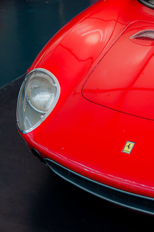 Free Close-up shot of a vintage red sports car showcasing its sleek design and iconic emblem. Stock Photo