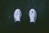 深色人行道背景上银色运动鞋的顶视图