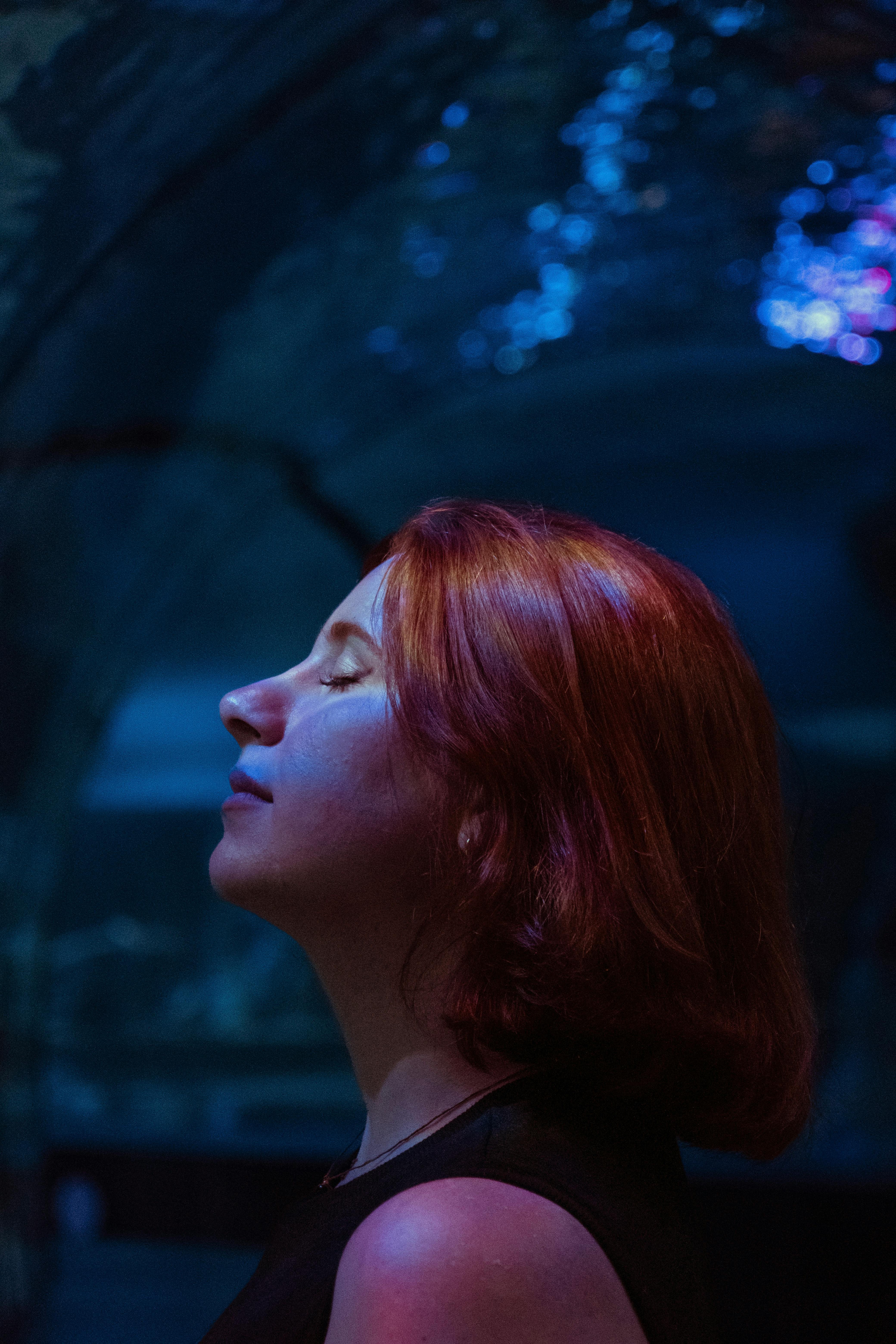 A contemplative redhead woman immersed in a mystical, dreamlike underwater setting.