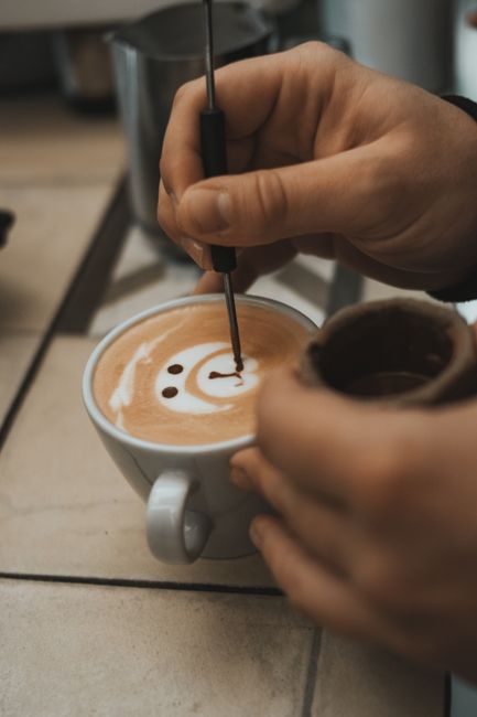 Close-up of a barista creating latte art on a coffee cup indoors.