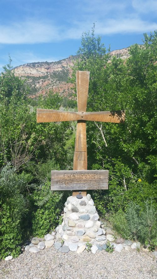 Free A wooden cross stands amidst lush greenery with mountains in the background. Stock Photo