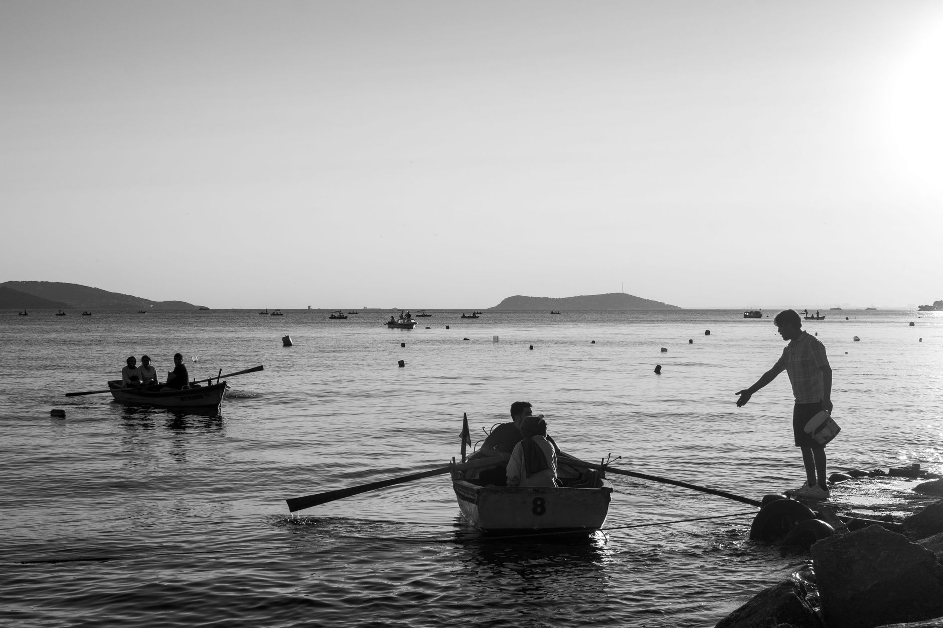 Silhouette of people enjoying a calm evening on the İstanbul coast with boats.