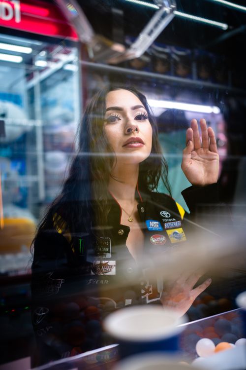 Free A thoughtful woman looks through an arcade game machine at night. Stock Photo