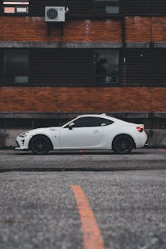 White sports car parked in urban area, showcasing sleek design and powerful aesthetics.