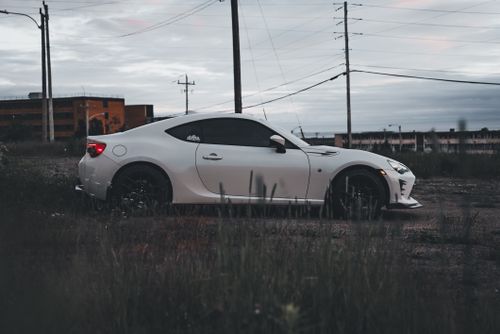 Free A white sports car parked in an urban area at dusk, showcasing its sleek design and modern aesthetic. Stock Photo