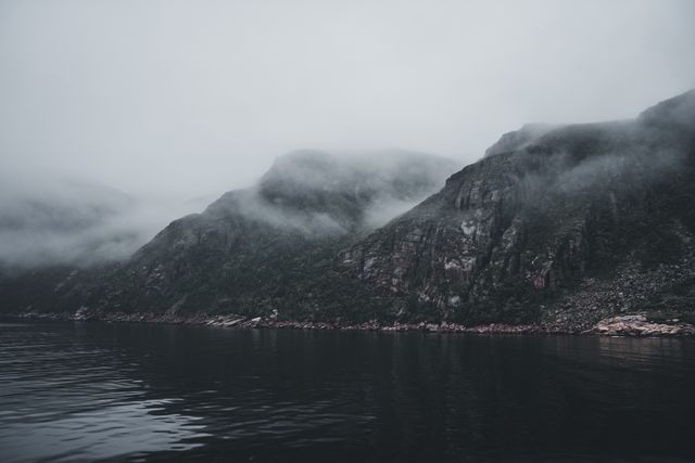Mist-shrouded mountains above a still lake — photo by Erik Mclean on Pexels