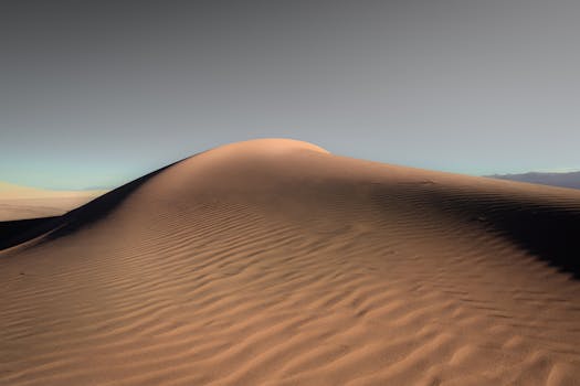 A tranquil sand dune landscape in a vast desert under a clear sky, capturing nature's beauty.