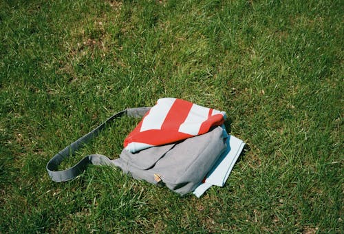 Grey Bag and Picnic Blanket Lying on Grass