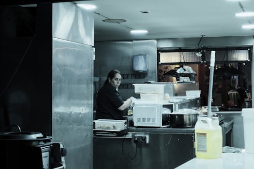 A chef working in a modern kitchen preparing meals for restaurant patrons.