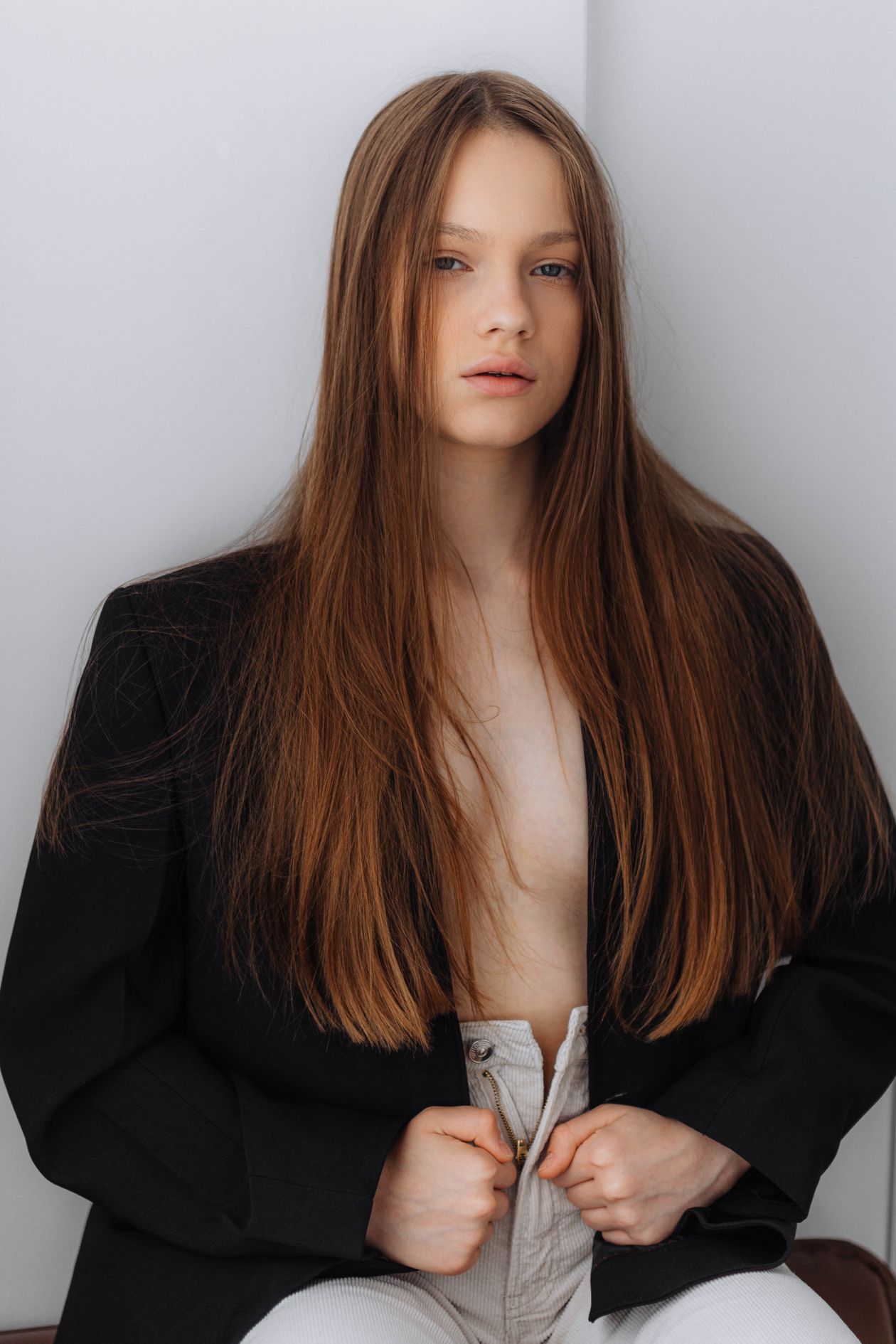 Woman in a minimalist black blazer and white pants in a clean studio setting editorial fashion