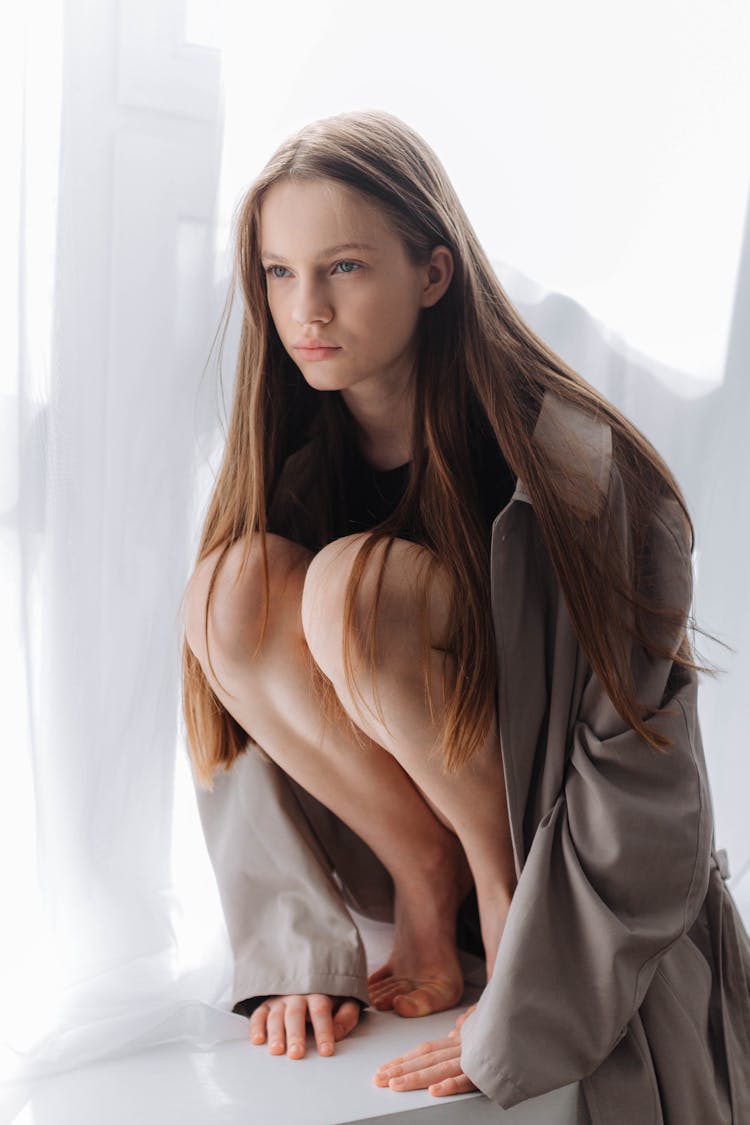 Photo Of A Girl Crouching By A Window