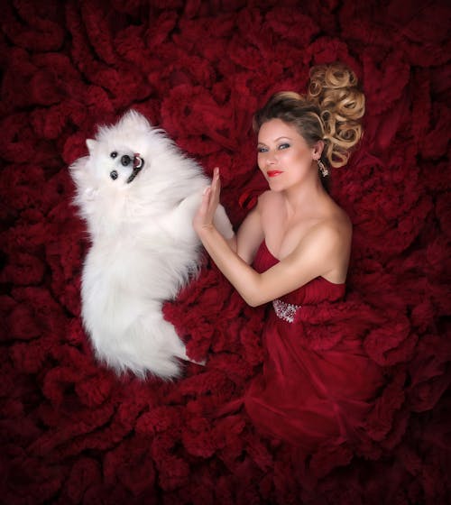 Woman in Red Dress Lying Down with White Dog