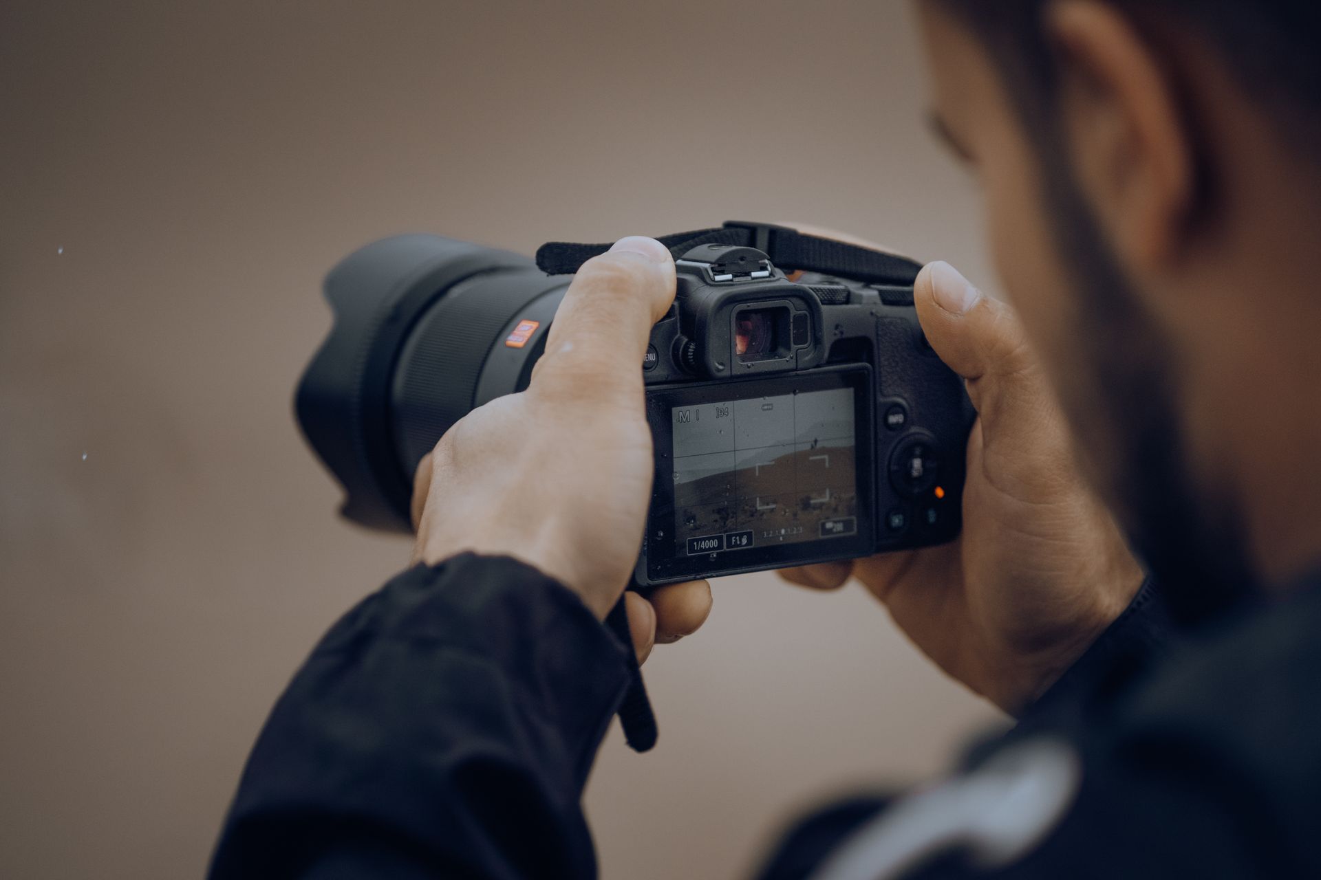 Detailed shot of a photographer adjusting settings on a digital camera outdoors.