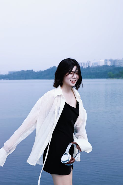 Portrait of a Pretty Brunette Standing on the Coast with Headphones in Hand