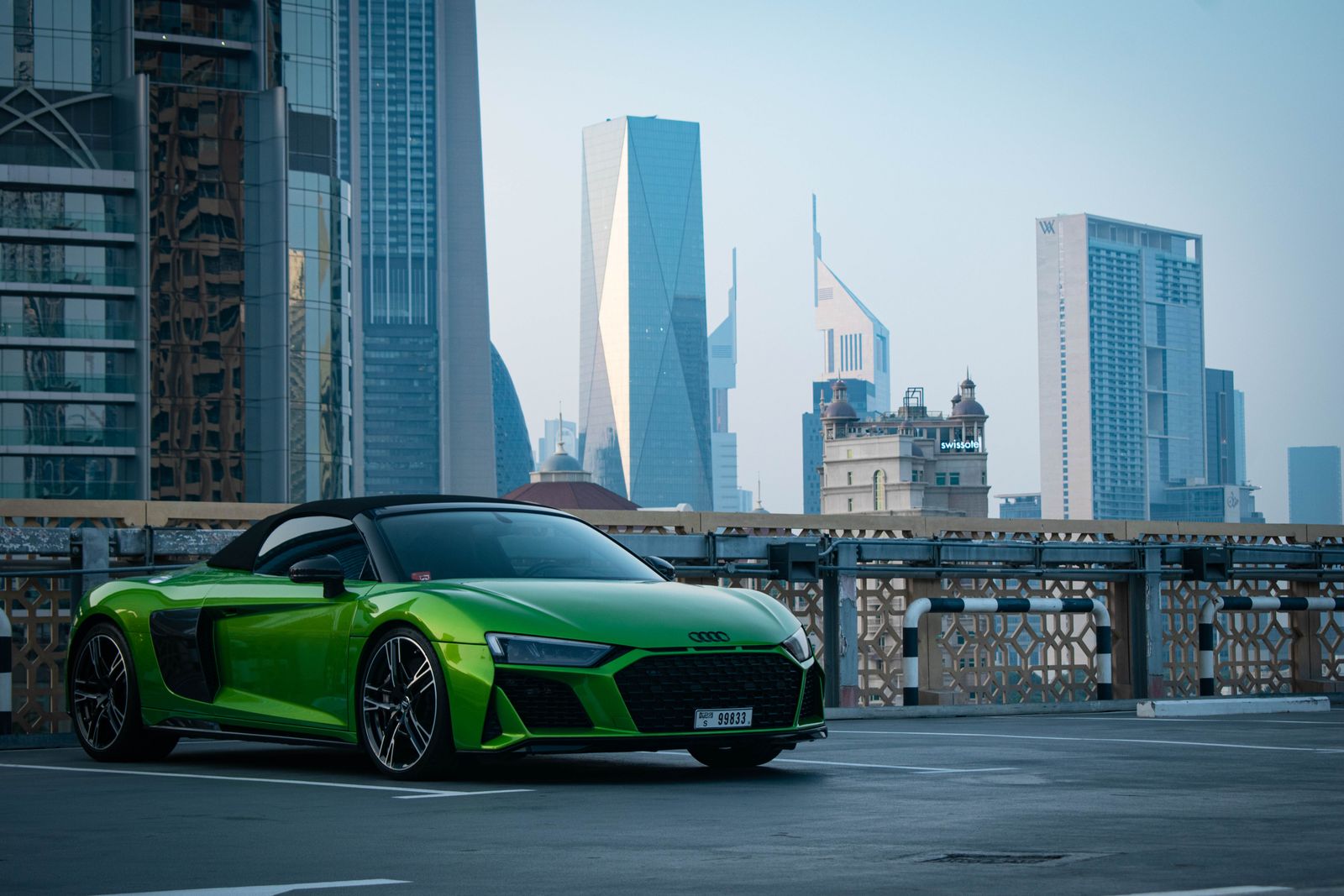 Green Audi R8 V10 Spyder parked in front of Dubai skyscrapers