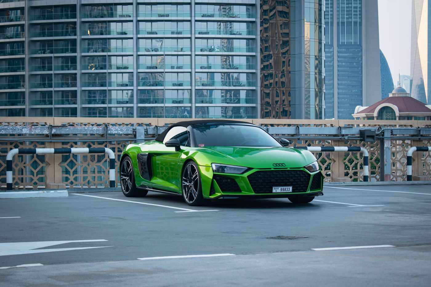 Green Audi R8 V10 Spyder against a Dubai street with towers behind