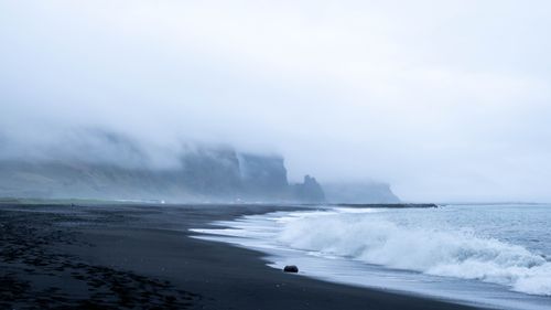 Free Misty black sand beach at Vik, Iceland showcasing waves and foggy cliffs. Stock Photo