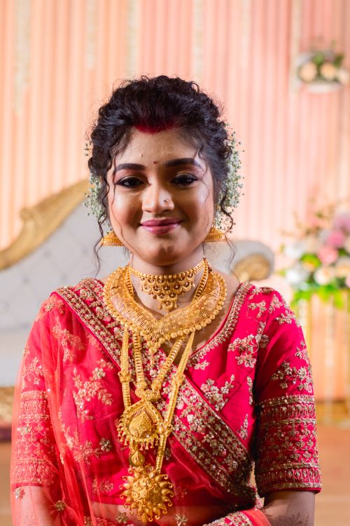 Free Beautiful Indian bride wearing traditional red saree and gold jewelry, smiling indoors. Stock Photo