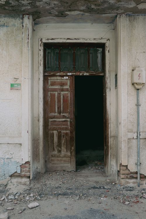 Free A vintage wooden door opening into a dark, abandoned building with textured walls. Stock Photo