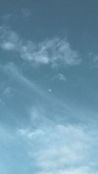 A serene view of the half moon amidst clouds in Houston, Texas.