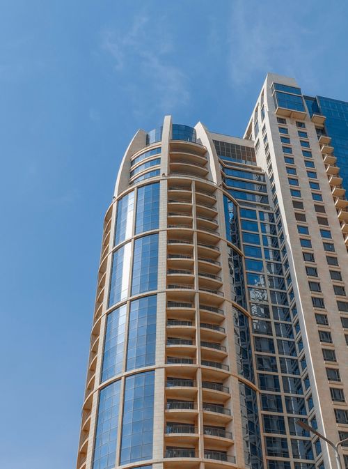 Free Low angle view of a modern skyscraper with a glass facade and clear blue sky. Stock Photo