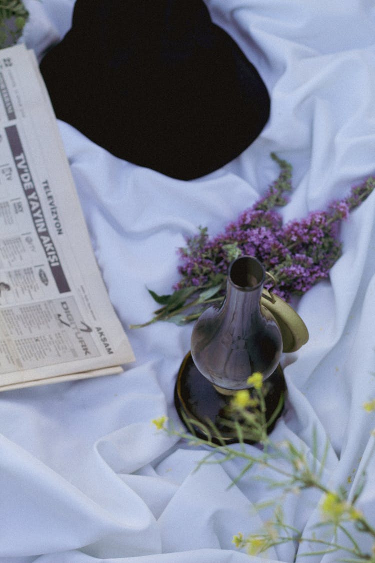 Hat, Newspaper And Vase On Picnic Blanket