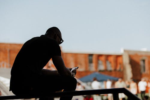 Silhouette of Man Sitting with Cellphone