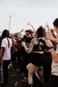 A vibrant crowd dancing and enjoying a lively outdoor concert under the sun.