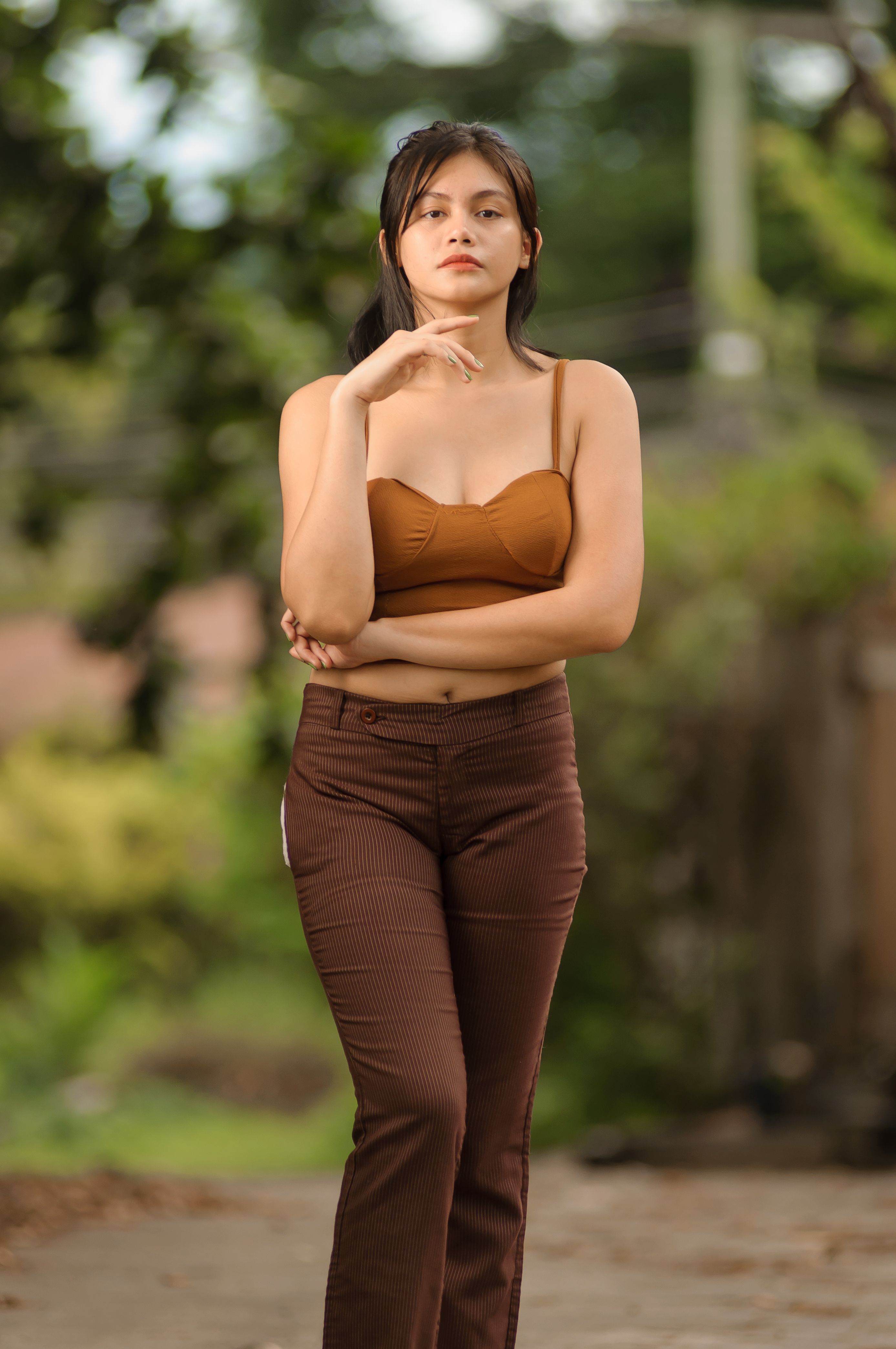 Confident woman in brown attire posing outdoors on a casual day.