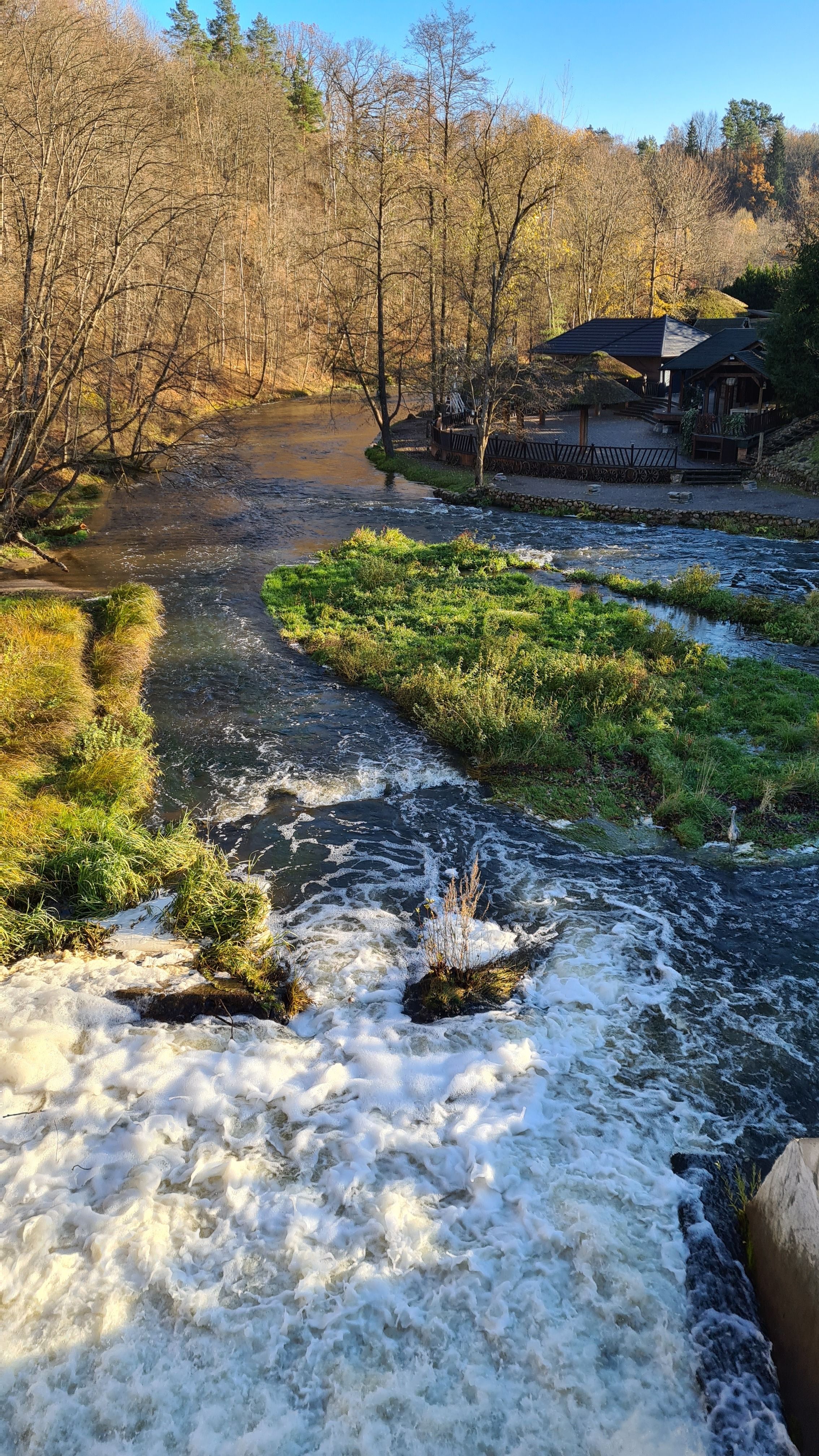 A breathtaking aerial shot of a cascading stream flowing through an autumn forest in Vilnius, Lithuania.