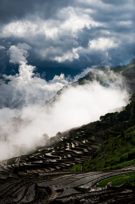 Clouds hover over dramatic terraced hills creating a striking landscape scene.
