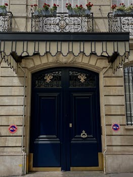 A stylish urban entrance featuring a blue door with a decorative balcony above it.