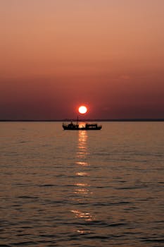 A tranquil boat silhouette against a stunning sunset over Lake Simcoe in Georgina, Ontario.