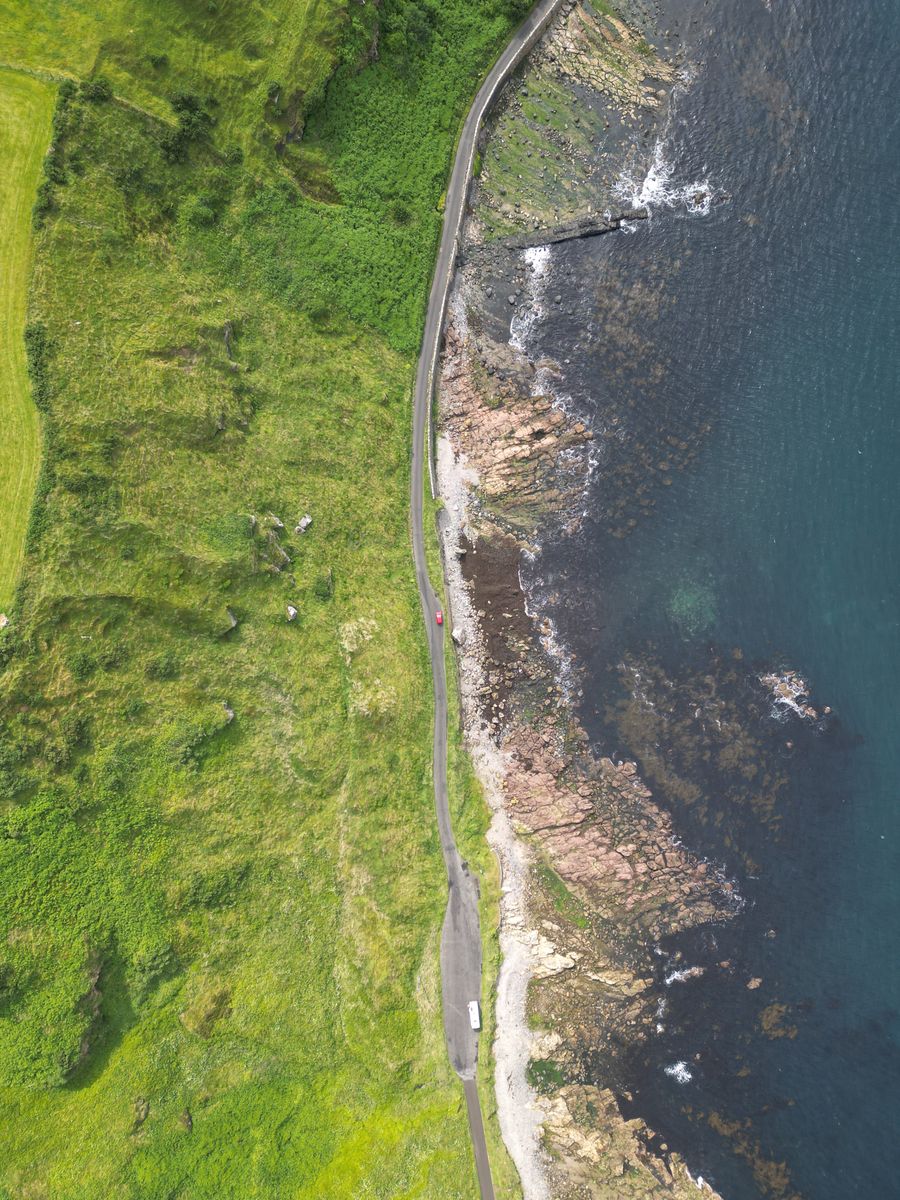 Aerial view of a green coastline meeting dark ocean, by Fabesh on Pexels