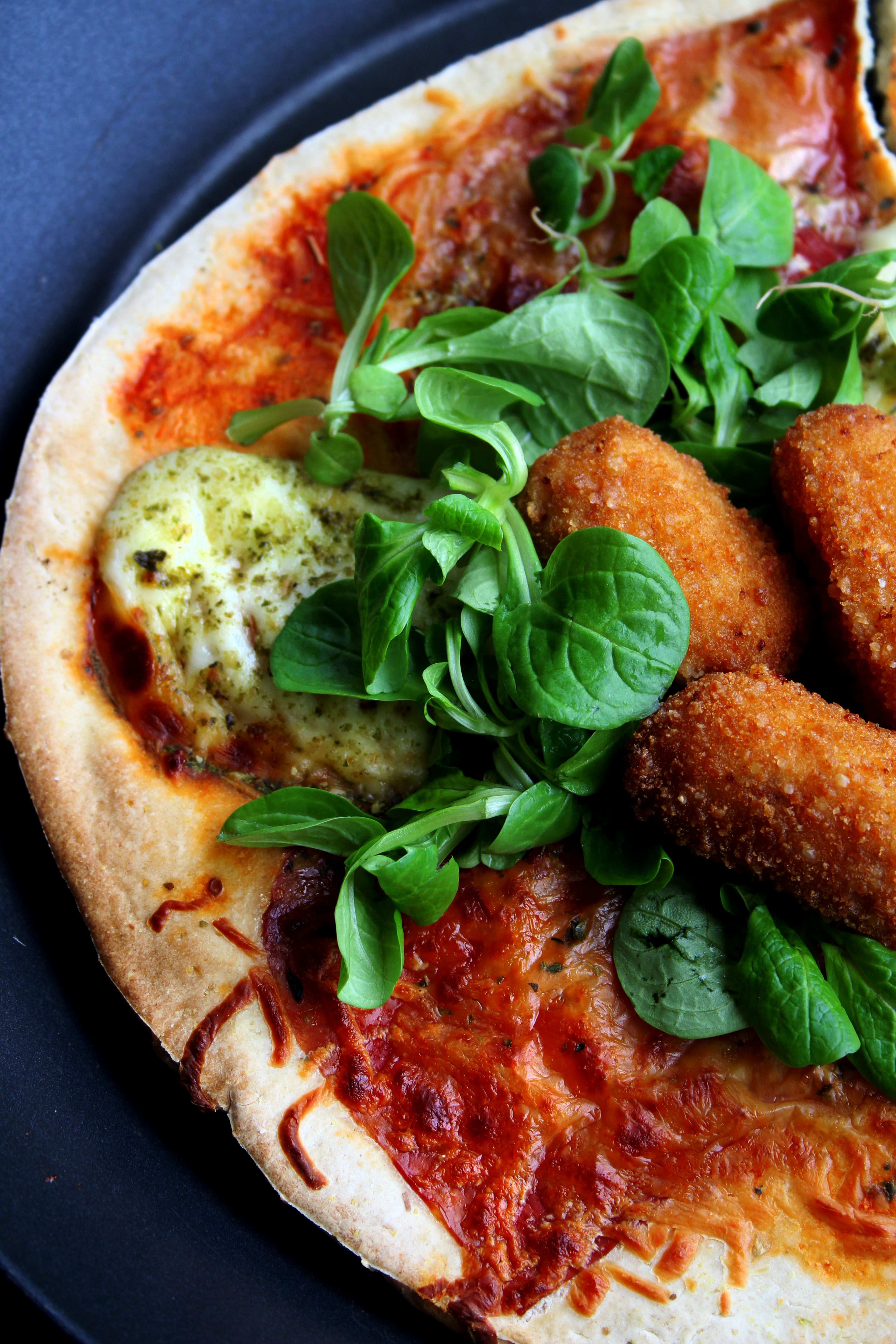 A mouthwatering close-up of pizza with fresh greens and crispy toppings.