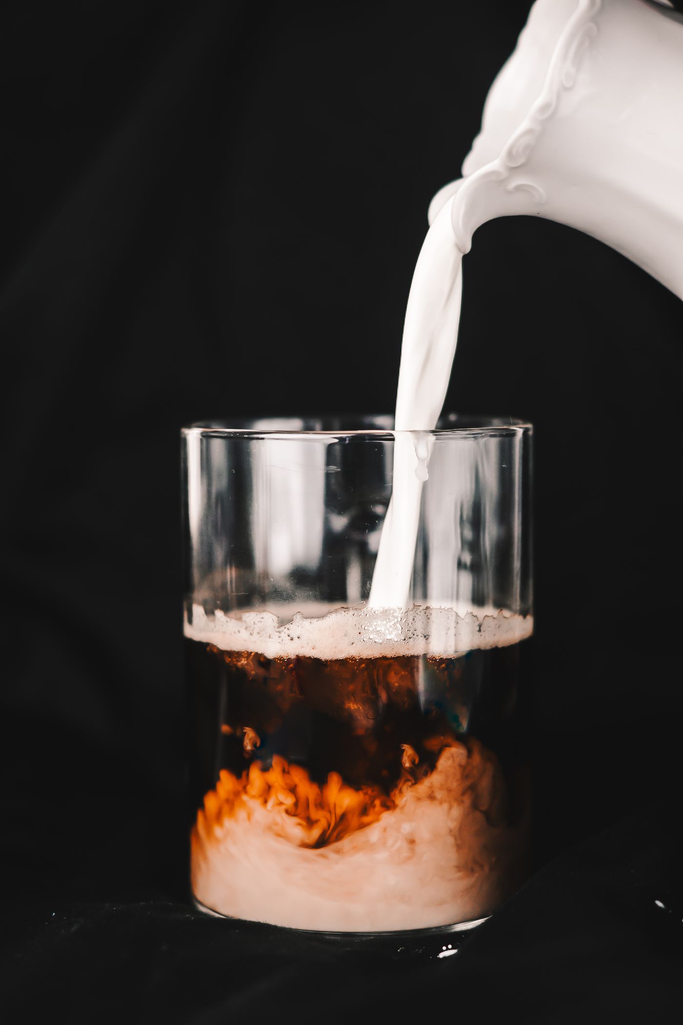 Close view of milk creating a swirl in dark coffee
