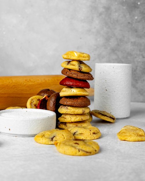 Free Vertical shot of assorted cookies stacked with a rolling pin on a light background. Perfect for food photography. Stock Photo