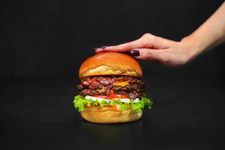 Womans Hand On A Hamburger 