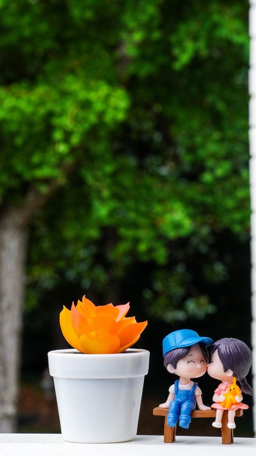 Free Adorable figures beside a vibrant potted plant on a sunny day. Stock Photo