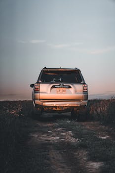 A silver SUV parked on a dirt road surrounded by twilight scenery, perfect for adventure themes.