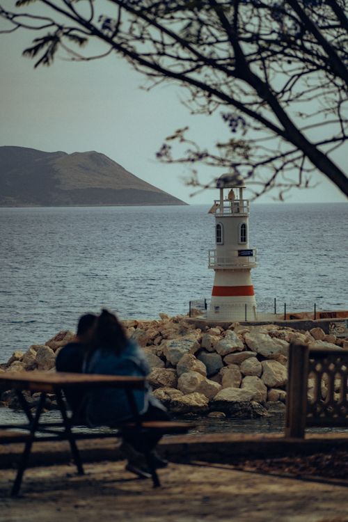Free A couple enjoys a romantic view of a quaint lighthouse on the coastline in Antalya, Turkey. Stock Photo