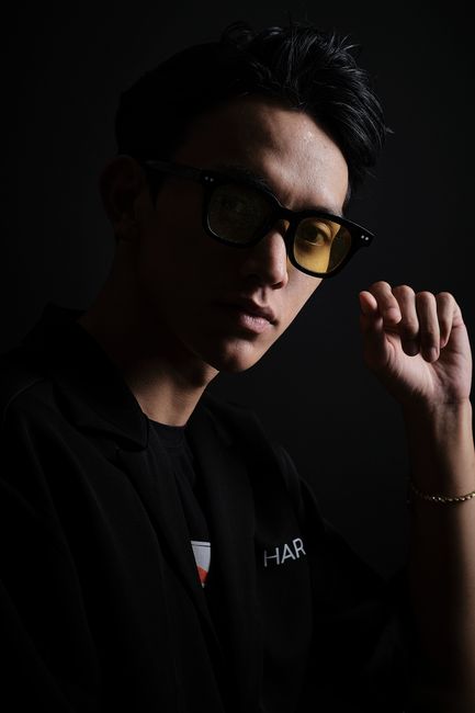 Moody portrait of a man wearing glasses with a dark, elegant vibe.