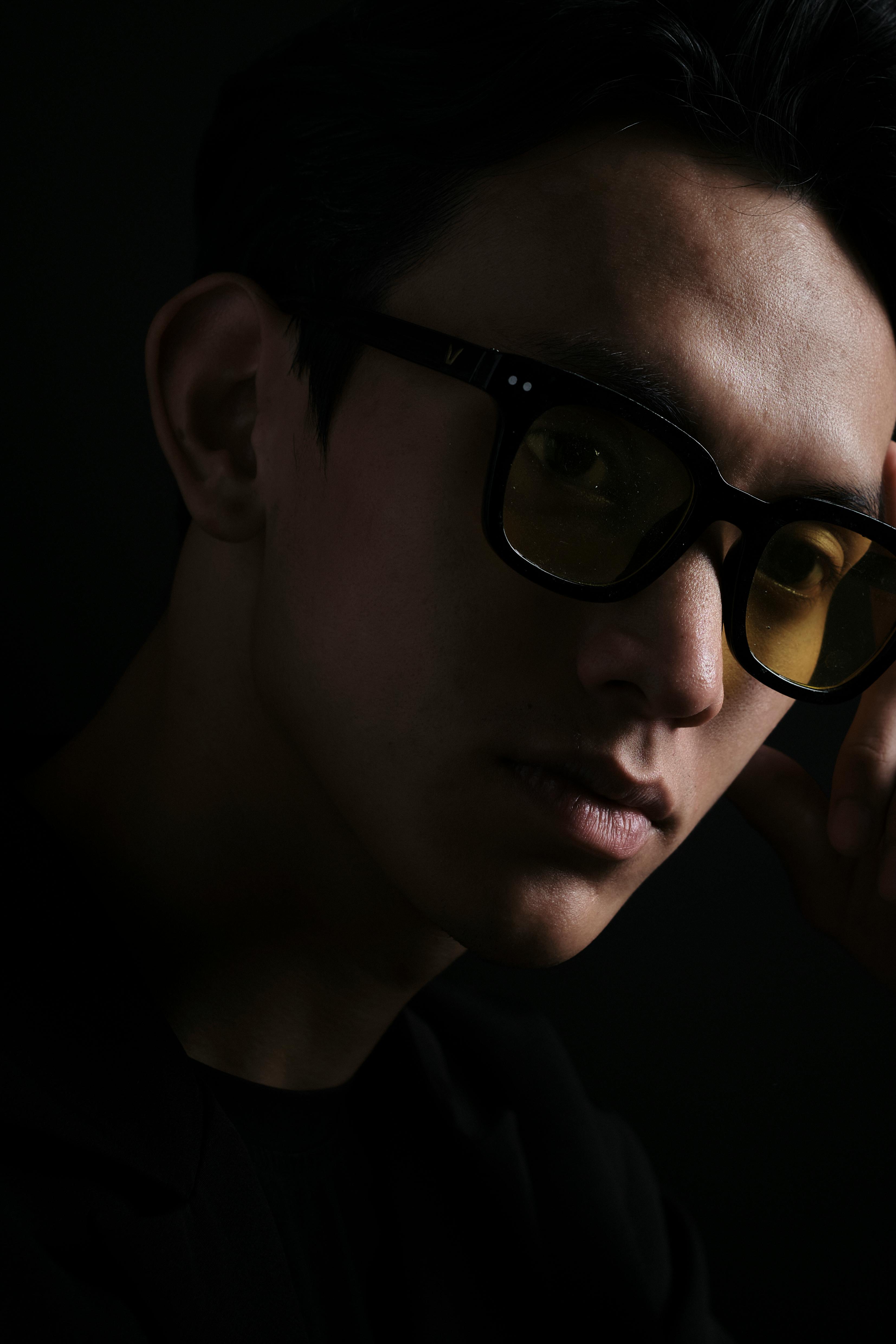 Dark and moody portrait of a man wearing iconic yellow sunglasses.