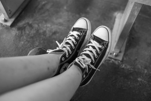 Free Close-up black and white photo of legs wearing stylish sneakers, urban feel. Stock Photo
