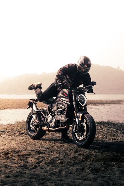 Free A motorcycle rider striking a dynamic pose by the riverbank. Stock Photo