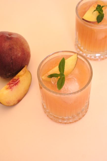 Glass of peach juice with mint on ice, perfect summer refreshment.