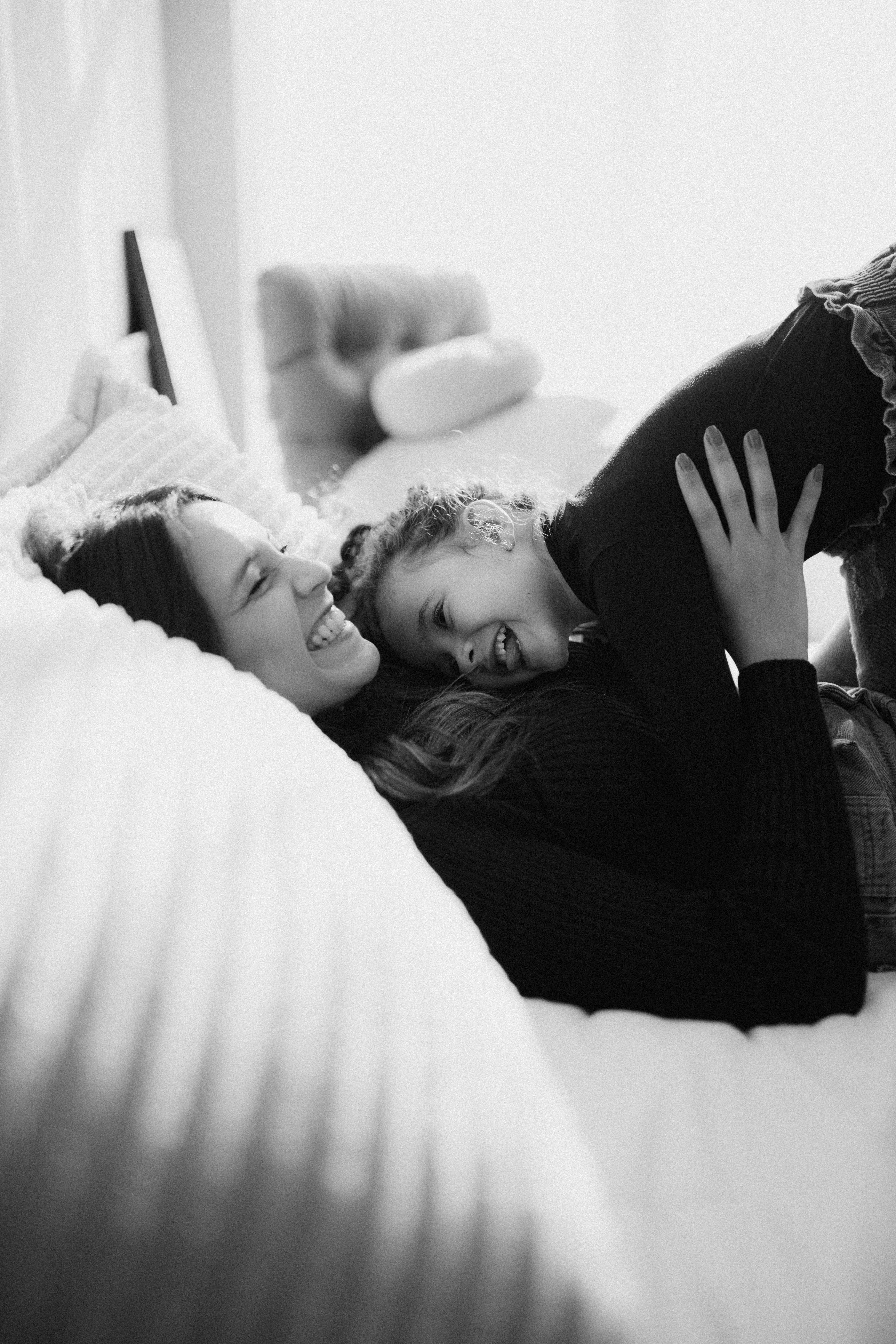 smiling mother playing with daughter on bed