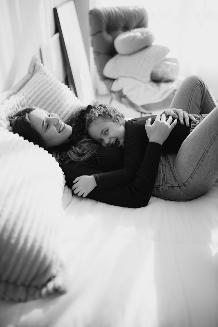 Mother Lying Down And Hugging Daughter On Bed